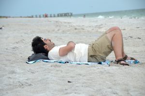 male student sleeping on the beach