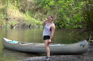 Female posing in front of a canoe.