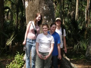 Four students posing in front of a large live oak.